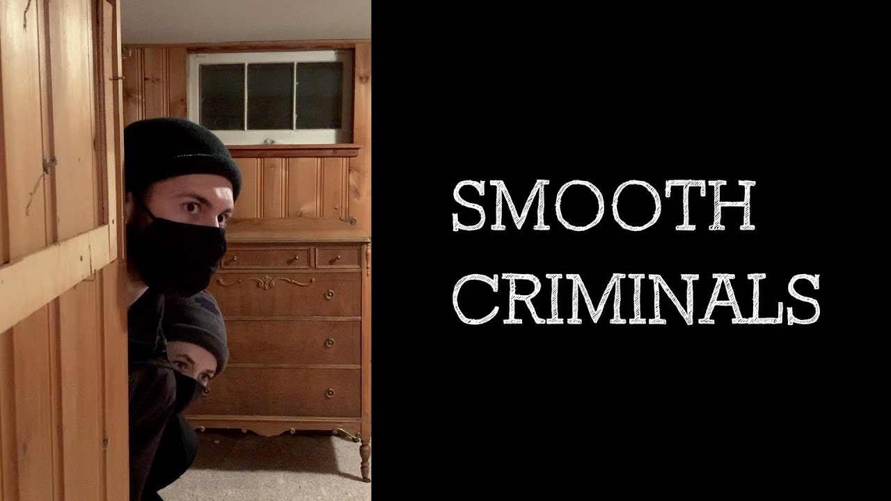 Two masked robbers peak around the corner in a room with wood-panel walls. White text on a black box reads "Smooth Criminals."